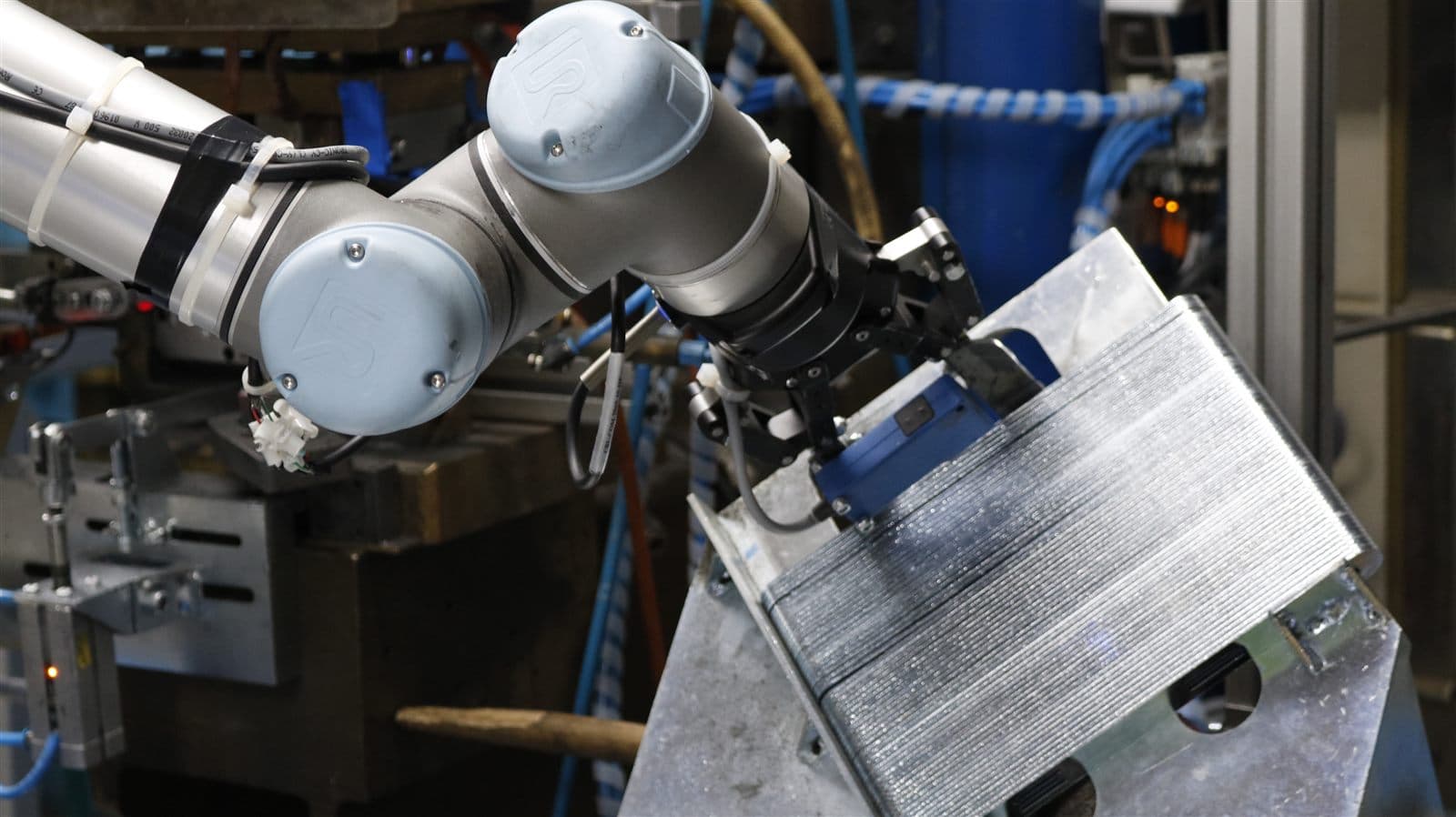 UR robotic arm with mounted vision camera inspecting a part